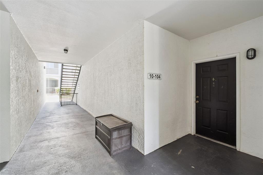 An exterior walkway leads to a black apartment door labeled 10-104 with a storage chest — 2603 MAITLAND CROSSROAD UNIT 104, ORLANDO, FL