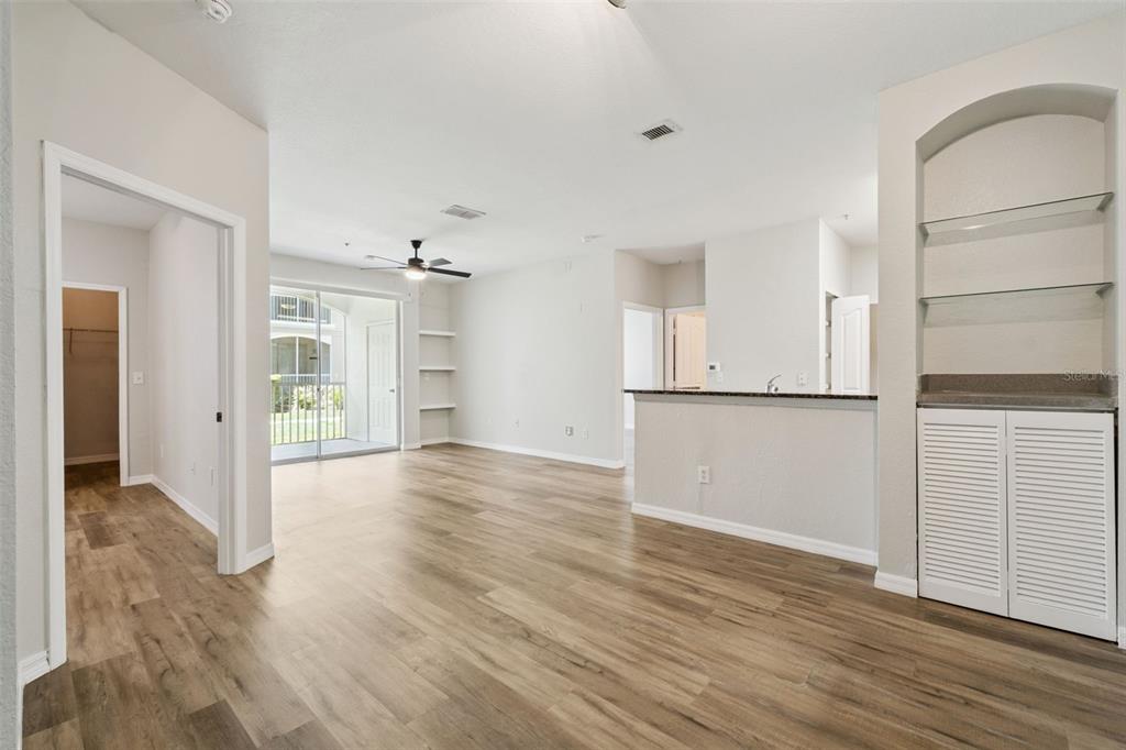 An open-concept living area features light wood-look flooring, a kitchen breakfast bar, and a balcony — 2603 MAITLAND CROSSROAD UNIT 104, ORLANDO, FL