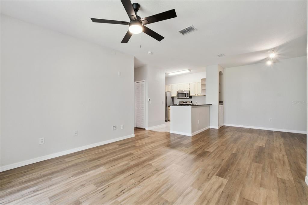 An open-concept living area features wood-look flooring, a ceiling fan, and an adjacent kitchen — 2603 MAITLAND CROSSROAD UNIT 104, ORLANDO, FL