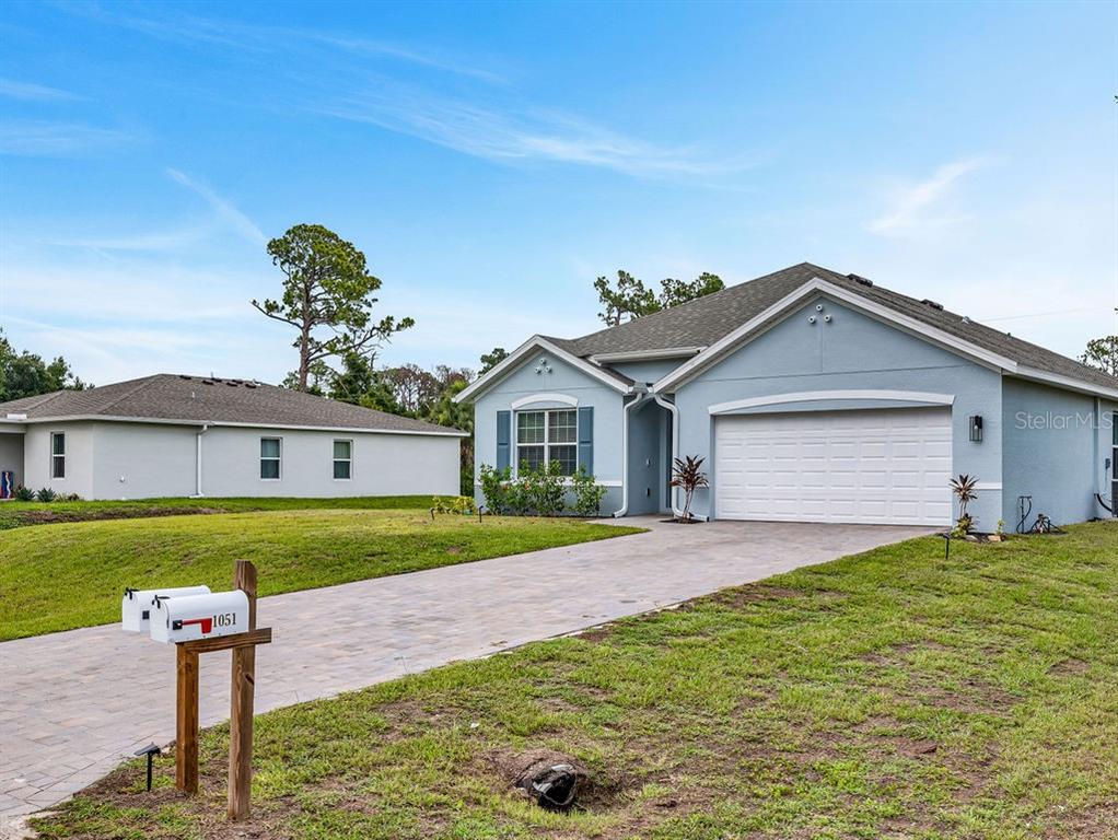 A light blue single-story house with a two-car garage and a paved driveway — 1048 ADALIA TERRACE, PORT CHARLOTTE, FL