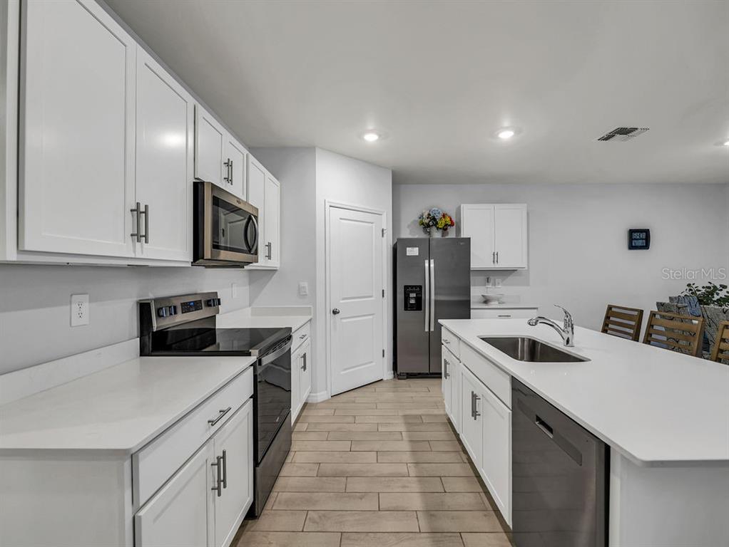 A modern kitchen features white cabinets, stainless steel appliances, and a large central island — 1048 ADALIA TERRACE, PORT CHARLOTTE, FL