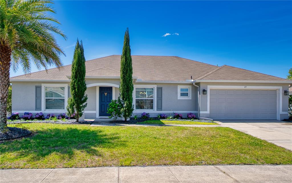 A single-story suburban house with a gray exterior, a two-car garage, and a landscaped yard — 27 LEWISDALE LANE, PALM COAST, FL