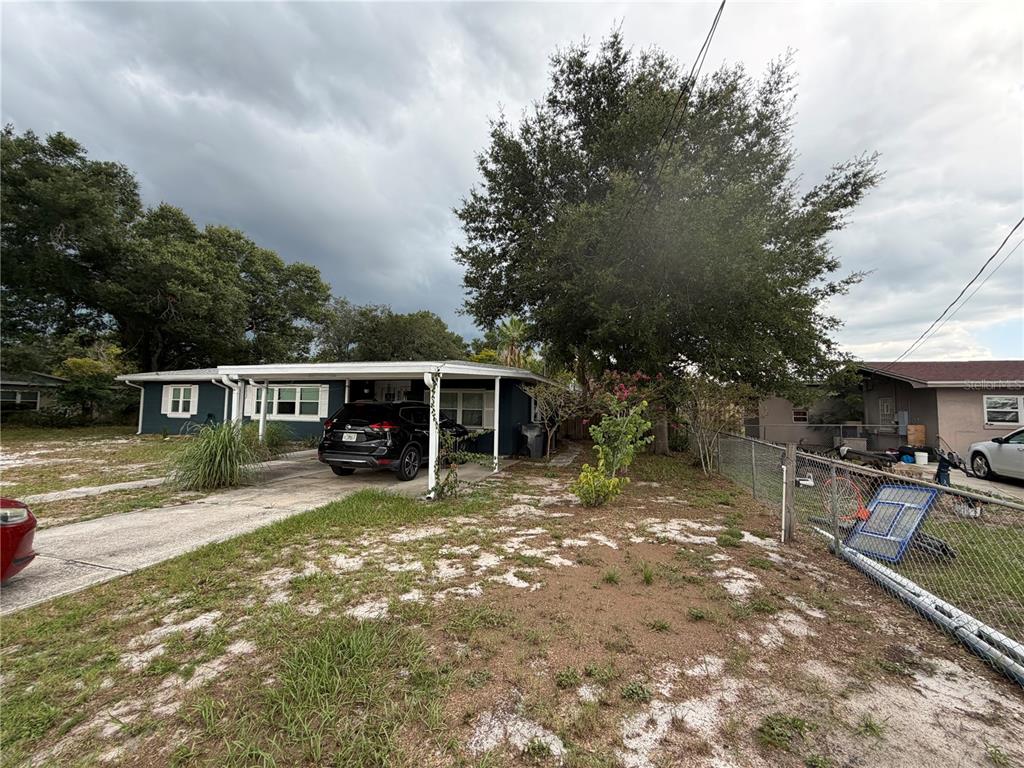 A single-story house with a carport, a dark exterior, and a large tree in front — 105 LAKE SEARS DRIVE, WINTER HAVEN, FL