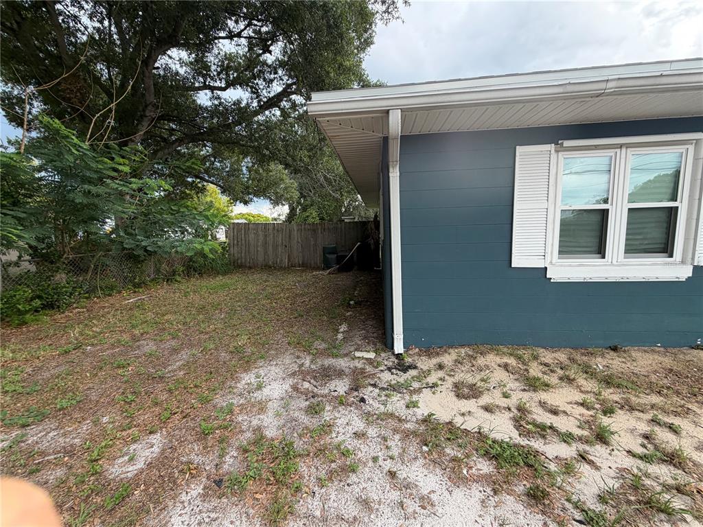 The exterior side of a blue house features a window and a grassy yard — 105 LAKE SEARS DRIVE, WINTER HAVEN, FL