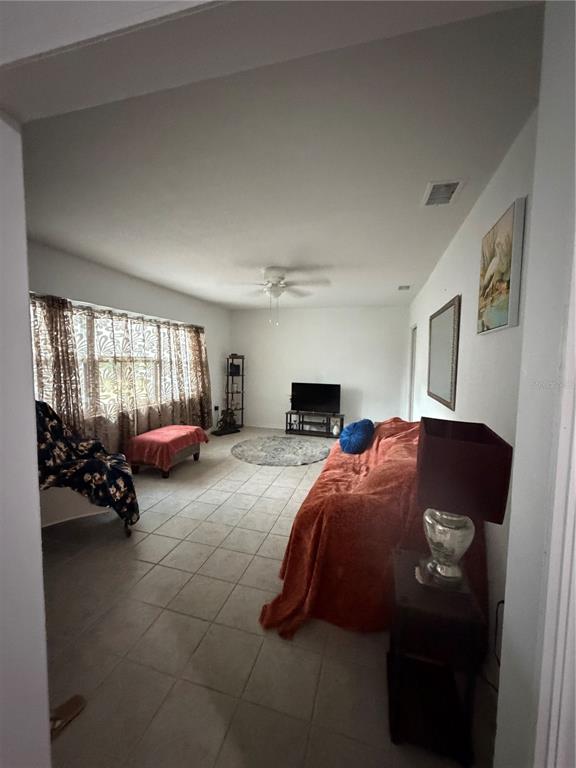A living room features tile flooring, a large window with patterned curtains, and a sofa — 105 LAKE SEARS DRIVE, WINTER HAVEN, FL