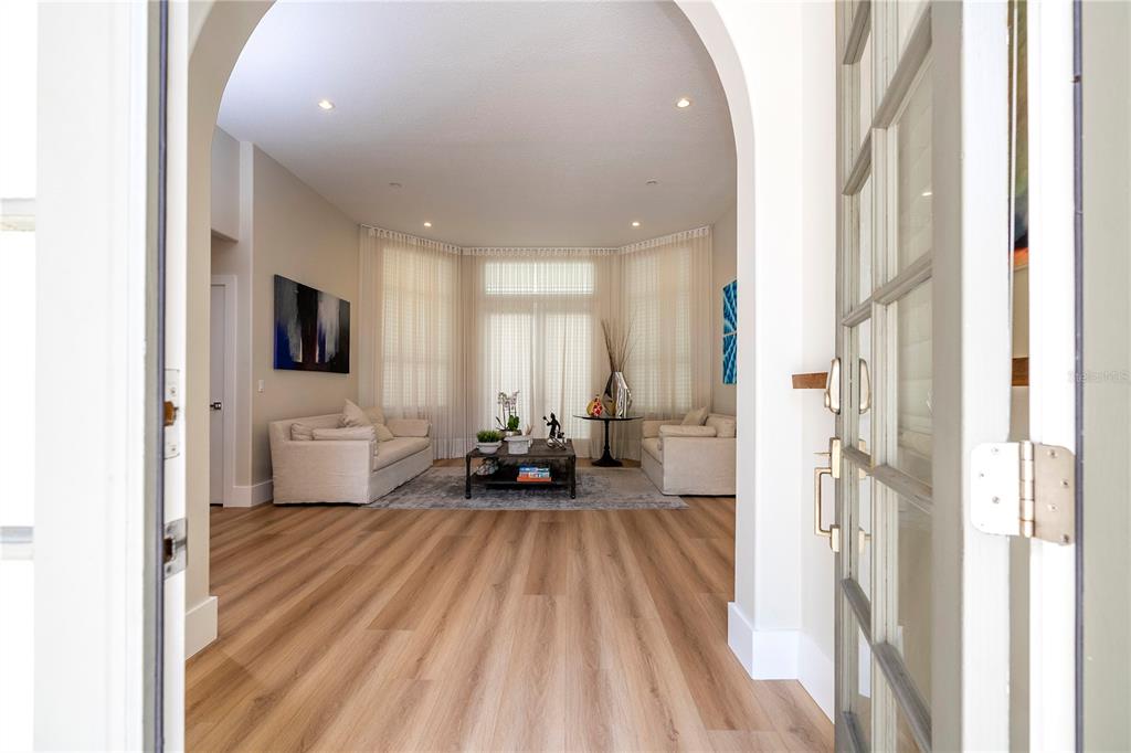 A view through an open doorway into a living room with light wood flooring — 8727 BECKINGHAM PLACE, ORLANDO, FL