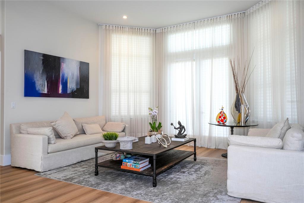 A living room features light-colored sofas, a dark wood coffee table, and floor-to-ceiling curtains — 8727 BECKINGHAM PLACE, ORLANDO, FL