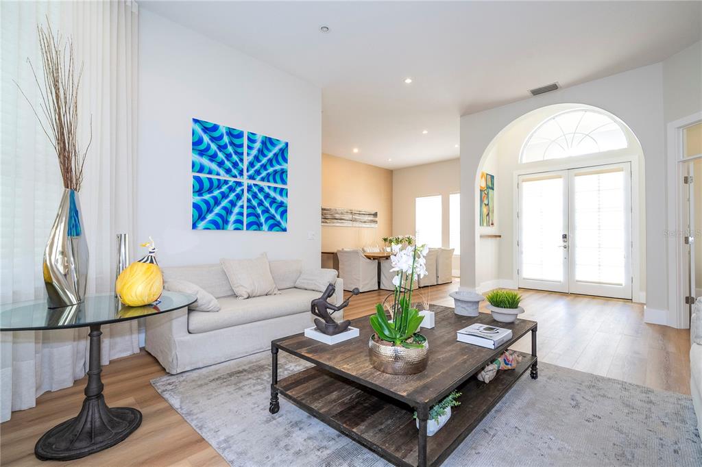 A living room features a beige sofa, a wooden coffee table, and blue wall art — 8727 BECKINGHAM PLACE, ORLANDO, FL