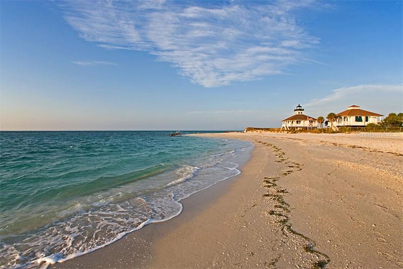 A sandy beach with gentle waves leads to two coastal houses under a blue sky — 115 BEAU RIVAGE DRIVE, ROTONDA WEST, FL