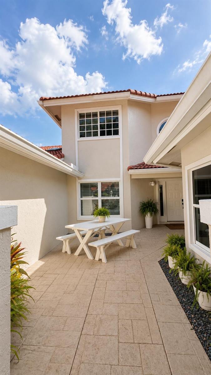 A white picnic table sits on a paved patio between two sections of a house — 4107 Carriage Drive # K2, Pompano Beach FL 33069, POMPANO BEACH, FL