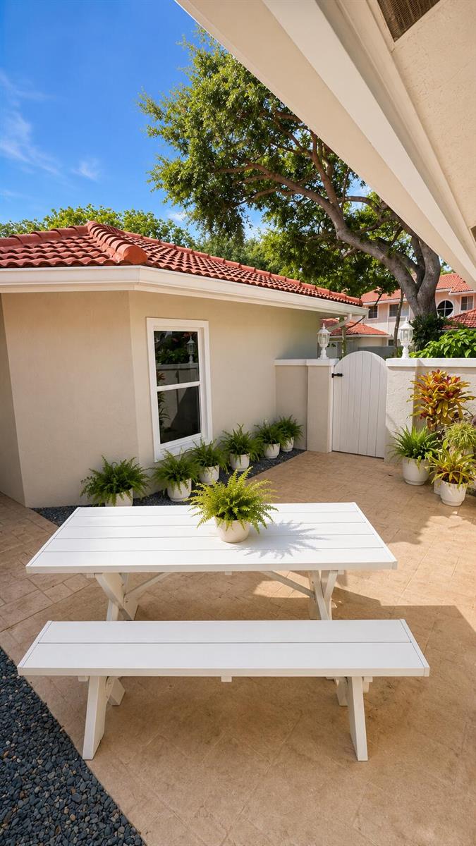 A white picnic table sits on a paved patio outside a house with a tiled roof — 4107 Carriage Drive # K2, Pompano Beach FL 33069, POMPANO BEACH, FL