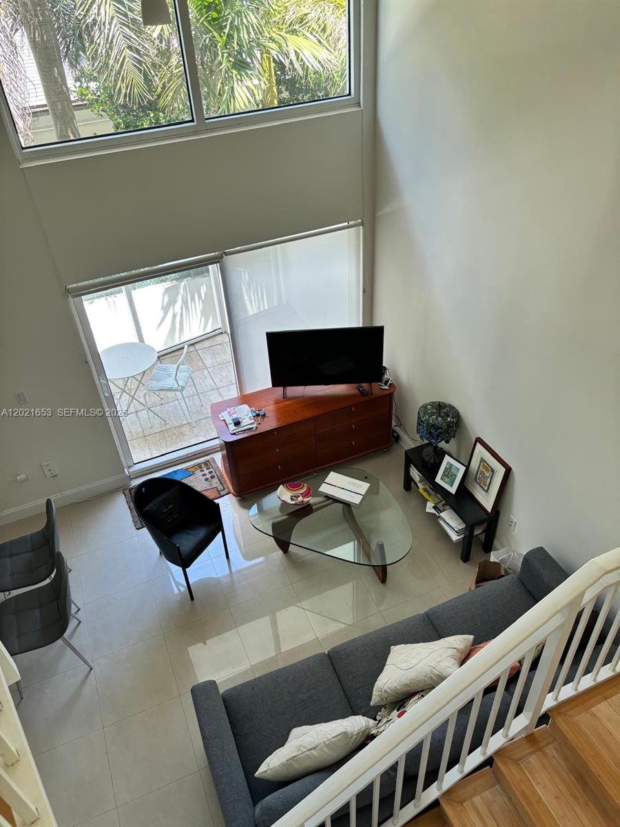 A high-angle view of a living room with a sofa, glass coffee table, and balcony — 1650 Brickell Ave # 110, Miami FL 33129, MIAMI, FL