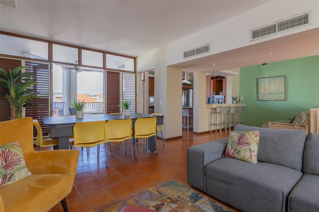 An open-concept living and dining area features tile floors, yellow chairs, and a gray sofa — 6000 RIO MAR BLVD VILLA LAS BRISAS UNIT 4A, RIO GRANDE, PR