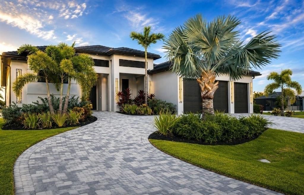A modern single-story house with a paver driveway, three-car garage, and tropical landscaping — 3123 SW 29TH AVENUE, CAPE CORAL, FL