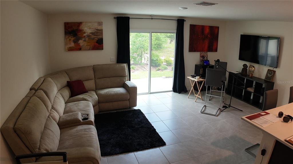 A living room features a beige sectional sofa, a black rug, and a wall-mounted television — 6569 SW 81ST LOOP, OCALA, FL