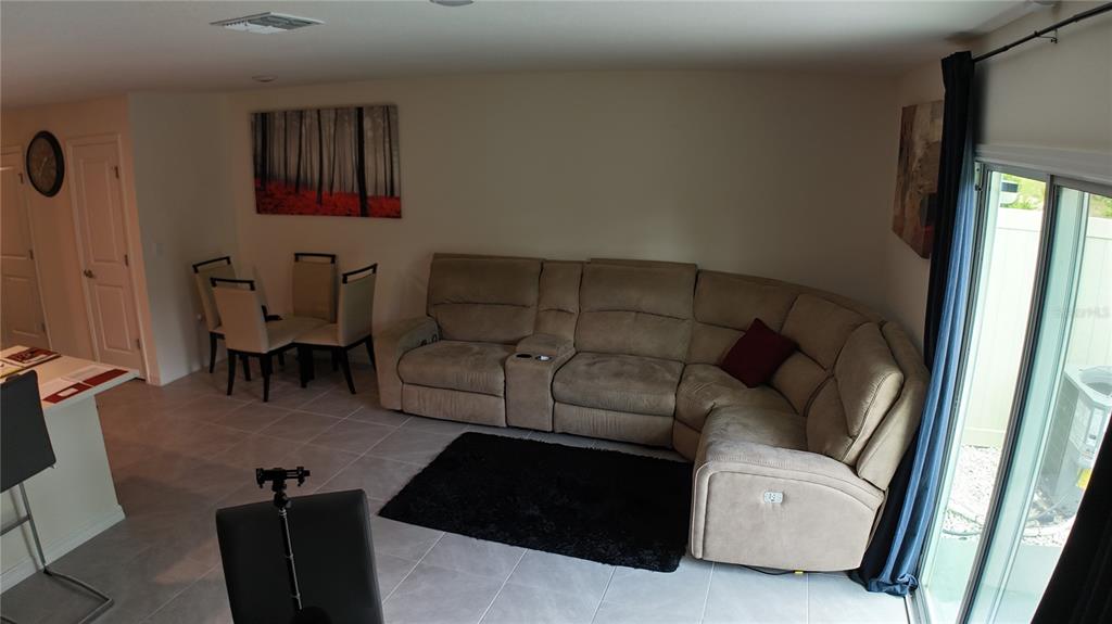 A living room with a beige sectional sofa, a black rug, and a dining area — 6569 SW 81ST LOOP, OCALA, FL