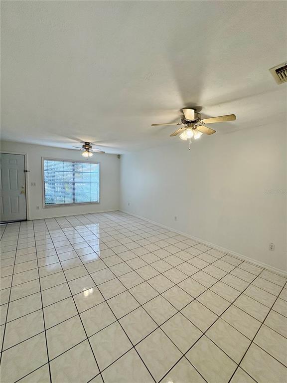 An empty room features white walls, a tiled floor, and two ceiling fans — 3243 FOREST OAKS COURT UNIT 117, WINTER PARK, FL