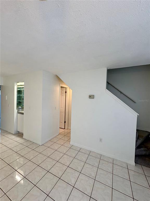 A tiled room features a staircase with a gray wall and a doorway leading elsewhere — 3243 FOREST OAKS COURT UNIT 117, WINTER PARK, FL