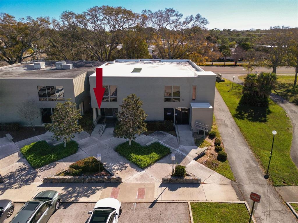 An aerial view shows the exterior of a multi-unit commercial building with a red arrow — 1964 BAYSHORE BOULEVARD UNIT B, DUNEDIN, FL