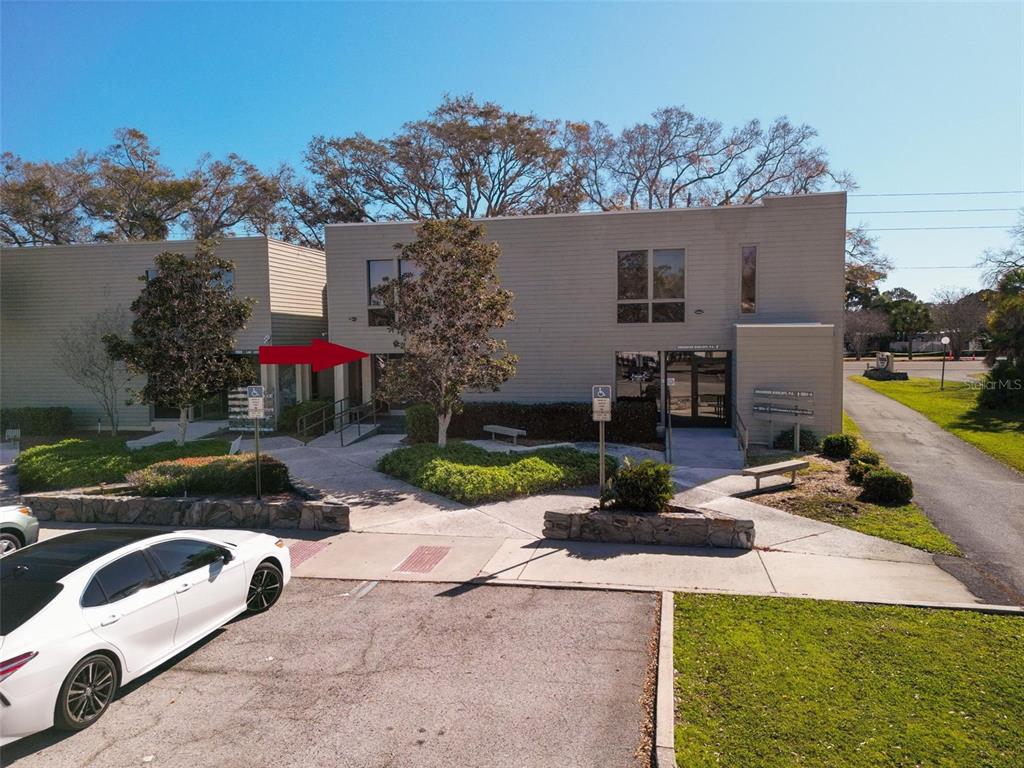 An exterior view of a two-story commercial office building with a red arrow pointing toward an entrance — 1964 BAYSHORE BOULEVARD UNIT B, DUNEDIN, FL