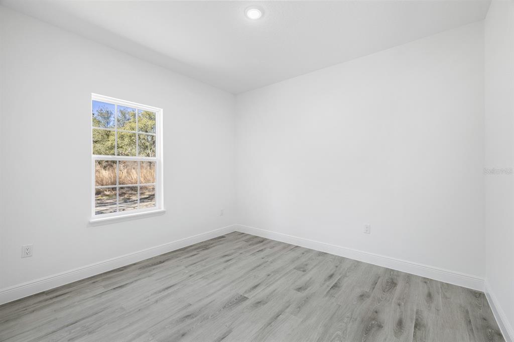 An empty room with white walls, gray wood-look flooring, and a single window — 144 W RUSKA PLACE, CITRUS SPRINGS, FL