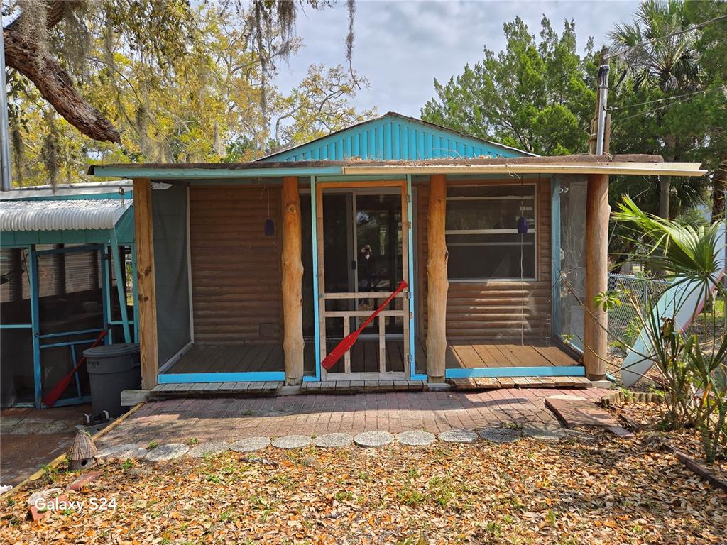 A small cabin with a screened-in porch, log-style siding, and a brick patio — 14365 & 14353 W EBBTIDE COURT, CRYSTAL RIVER, FL