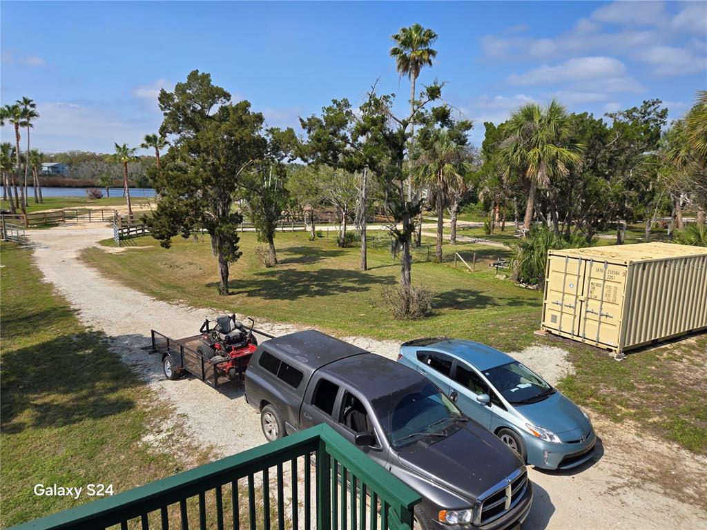 An elevated view shows a gravel driveway with a truck, trailer, and car near a container — 14365 & 14353 W EBBTIDE COURT, CRYSTAL RIVER, FL
