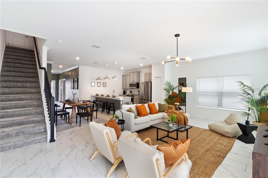 An open-concept living room and kitchen featuring a staircase, dining area, and modern decor — 4184 PARAGRAPH DRIVE, KISSIMMEE, FL