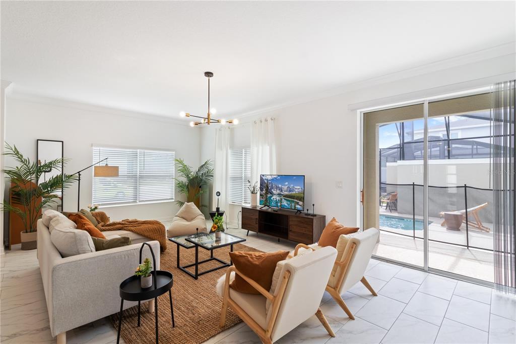 A bright living room features a sofa, two armchairs, a television, and a sliding glass door — 4184 PARAGRAPH DRIVE, KISSIMMEE, FL