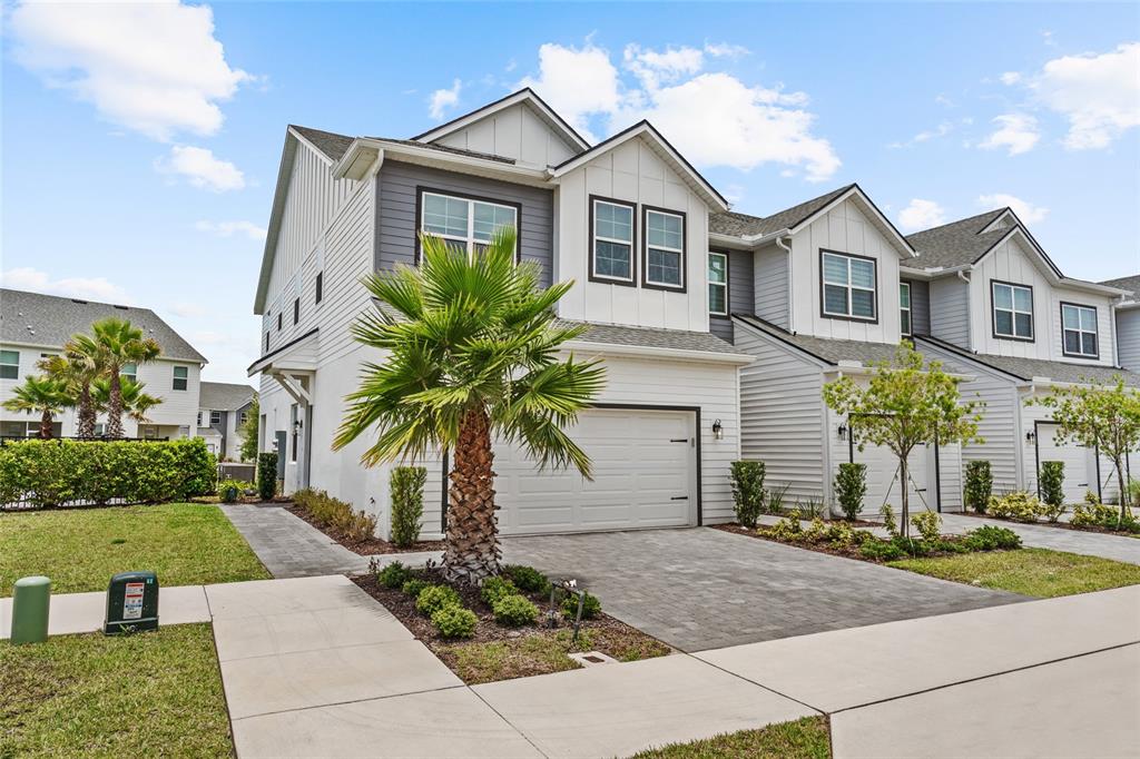 A row of two-story townhomes with white garages, gray siding, and palm trees in front — 1470 BROOKDALE COURT, OVIEDO, FL