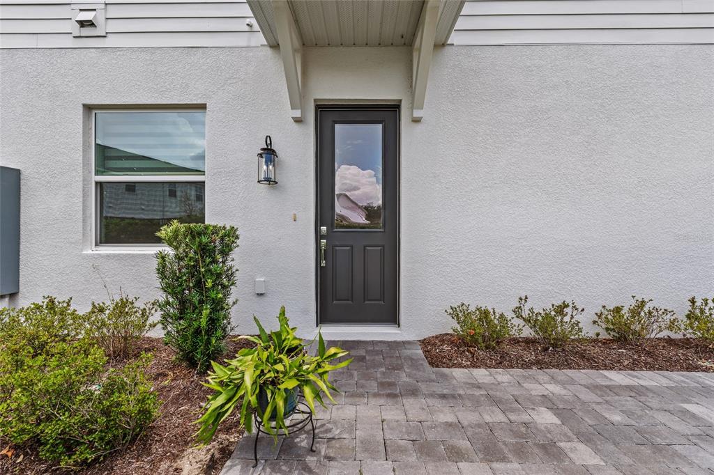 A gray front door with a glass panel is centered on a white stucco exterior — 1470 BROOKDALE COURT, OVIEDO, FL