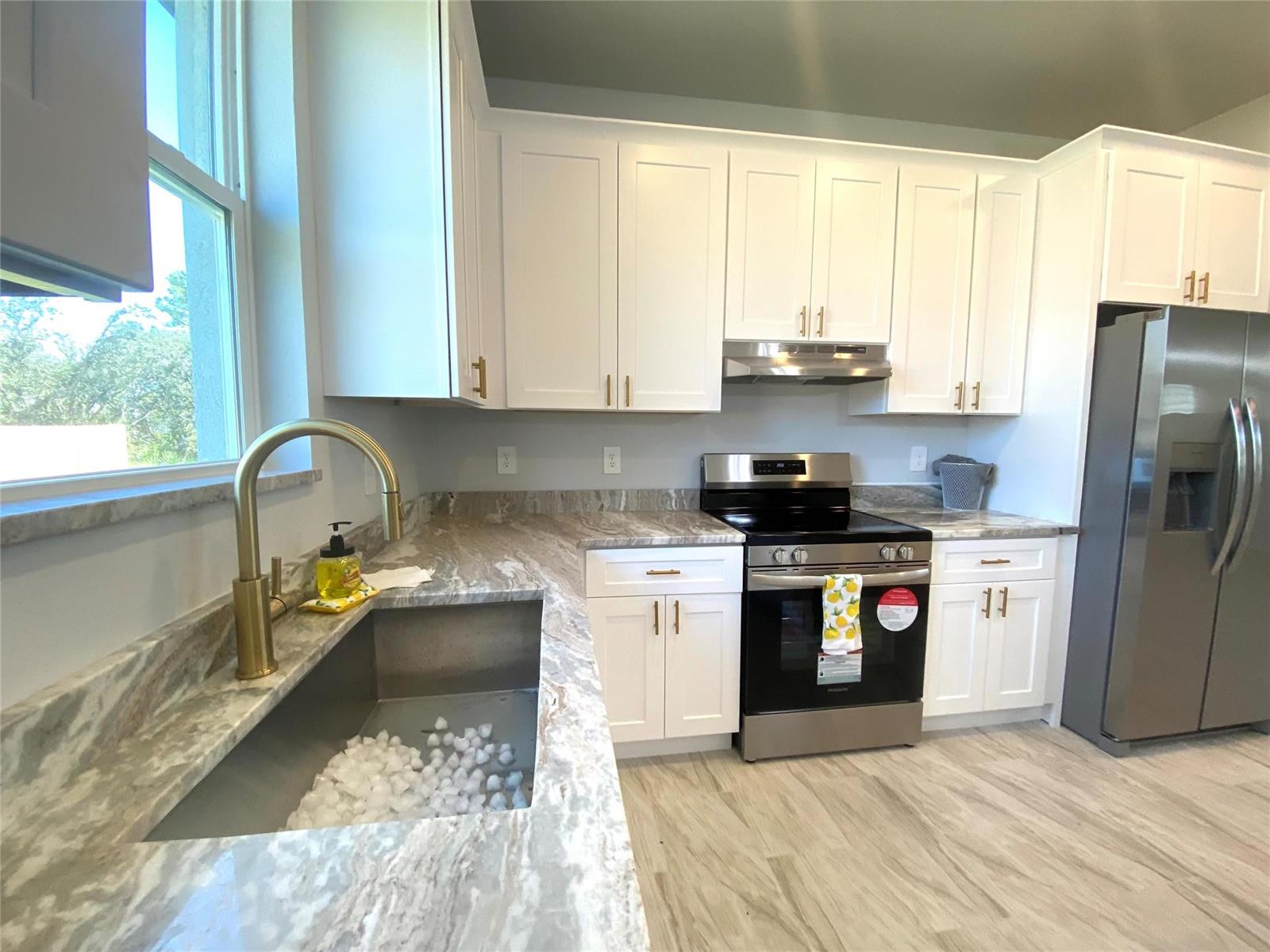 A kitchen features white cabinets, stone countertops, stainless steel appliances, and a gold faucet — 4229 Elson Avenue, Sebring FL 33875, SEBRING, FL