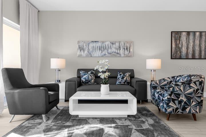 A living room features a dark sofa, two armchairs, a white coffee table, and wall art — 8762 WORLDQUEST BOULEVARD UNIT 6204, ORLANDO, FL