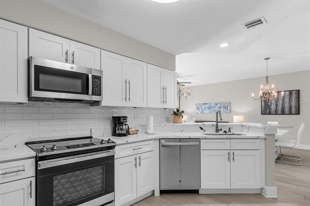 A kitchen with white cabinets, stainless steel appliances, and a white subway tile backsplash — 8762 WORLDQUEST BOULEVARD UNIT 6204, ORLANDO, FL