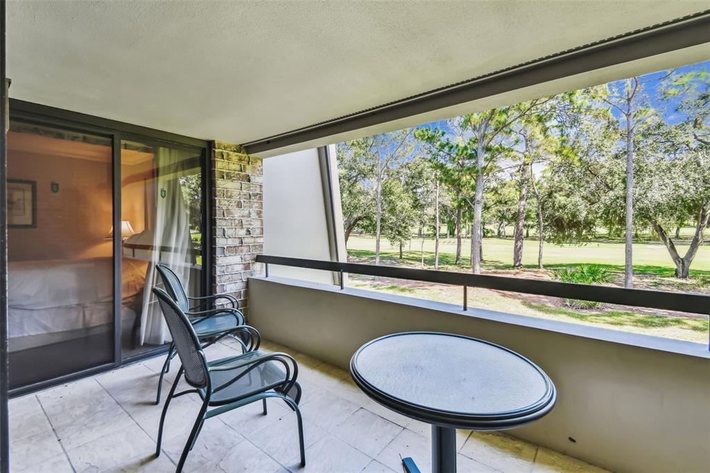 A balcony with two chairs and a small table overlooks a golf course — 36750 US HIGHWAY 19 N UNIT 19213, PALM HARBOR, FL