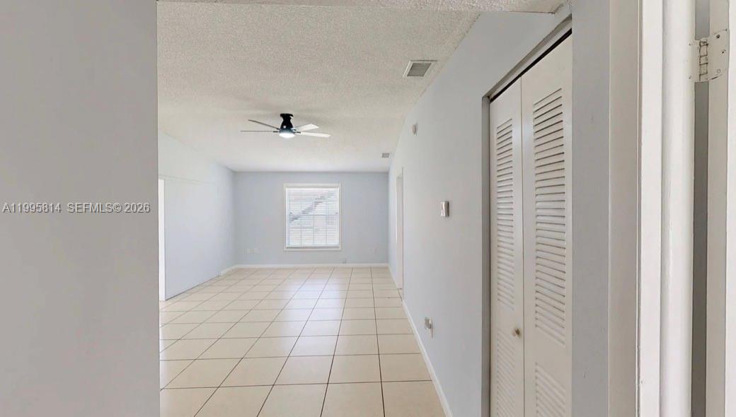 A hallway with tiled floors leads to a living area featuring a ceiling fan — 9481 W Fern Ln, Miramar FL 33025, MIRAMAR, FL