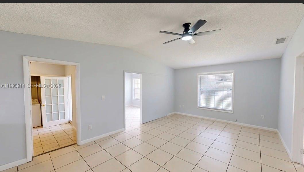 An empty room with light-colored tile flooring, a ceiling fan, and two doorways — 9481 W Fern Ln, Miramar FL 33025, MIRAMAR, FL
