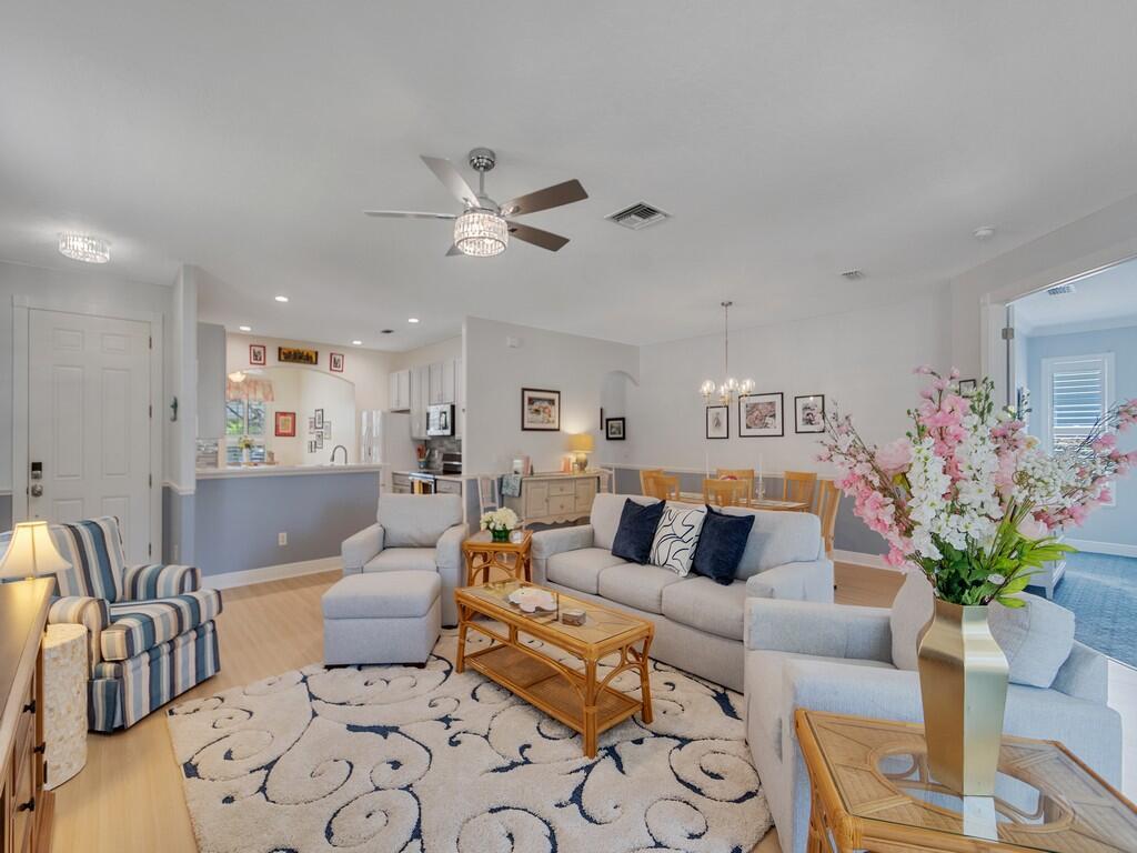 A bright living room features a light-colored sofa, patterned area rug, and an open kitchen — 7780 14th Lane, Vero Beach FL 32966, VERO BEACH, FL