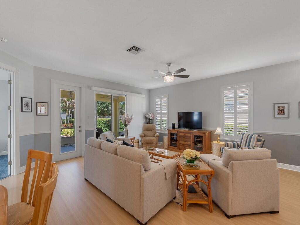 A living room features light-colored sofas, a wooden media console, and light wood flooring — 7780 14th Lane, Vero Beach FL 32966, VERO BEACH, FL