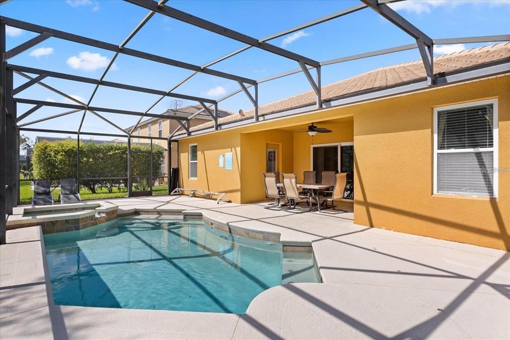 A screened-in patio features a swimming pool, a hot tub, and an outdoor dining set — 9122 STROMBOLI COURT, KISSIMMEE, FL