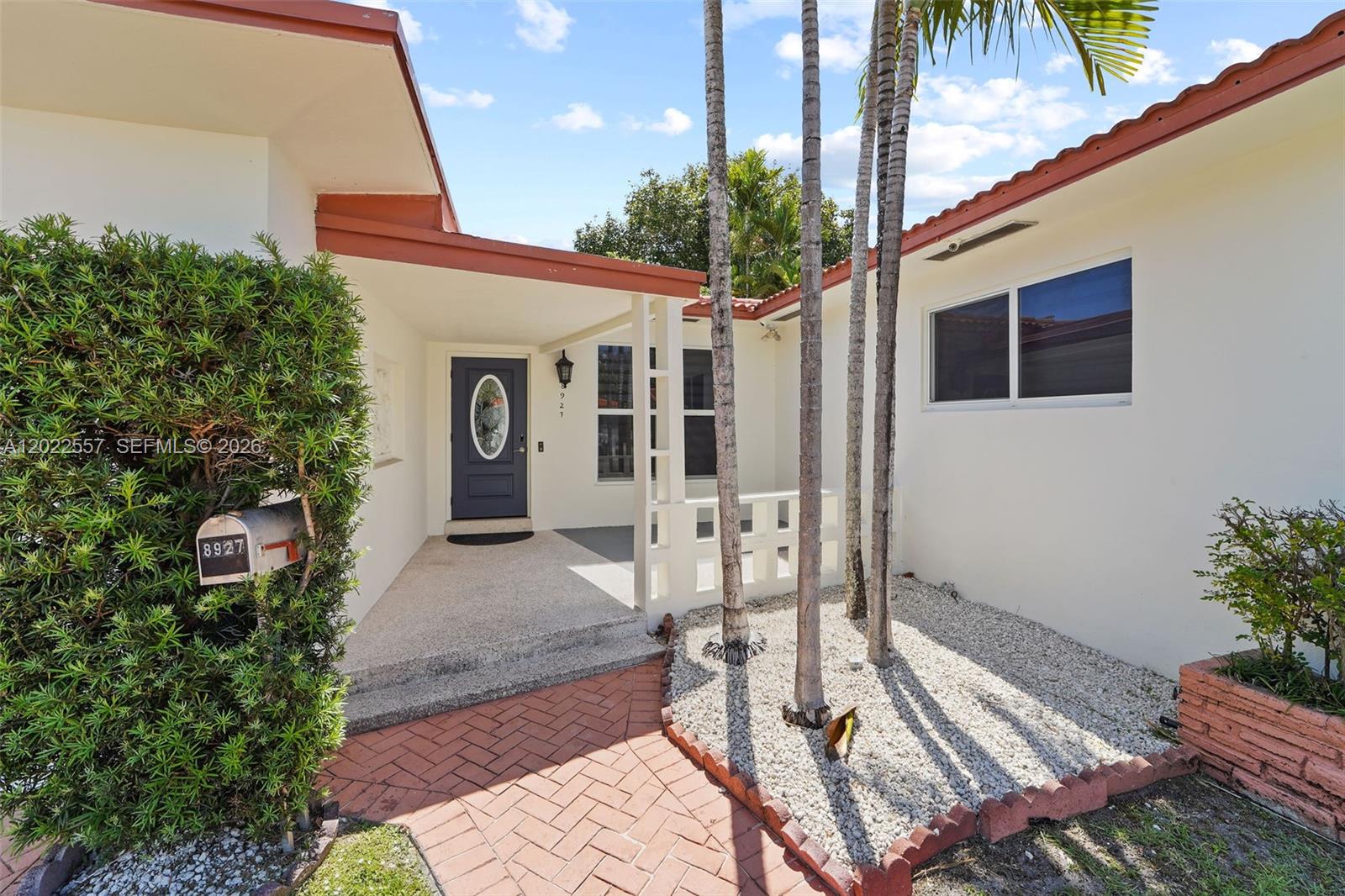 The exterior view shows a house entrance with a brick walkway and palm trees — 8927 Carlyle Ave, Surfside FL 33154, SURFSIDE, FL