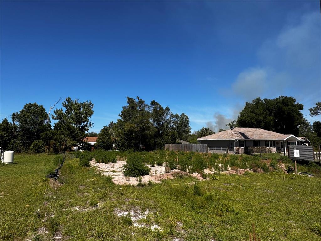 A grassy lot with a garden patch sits in front of a single-story residential house — 250 WILLIAMS AVENUE, ORANGE CITY, FL