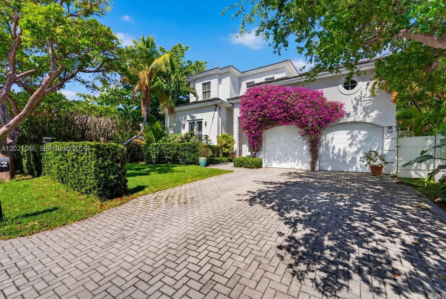 A two-story house with a paved driveway, white garage doors, and vibrant purple bougainvillea — 442 Ridgewood Rd, Key Biscayne FL 33149, KEY BISCAYNE, FL