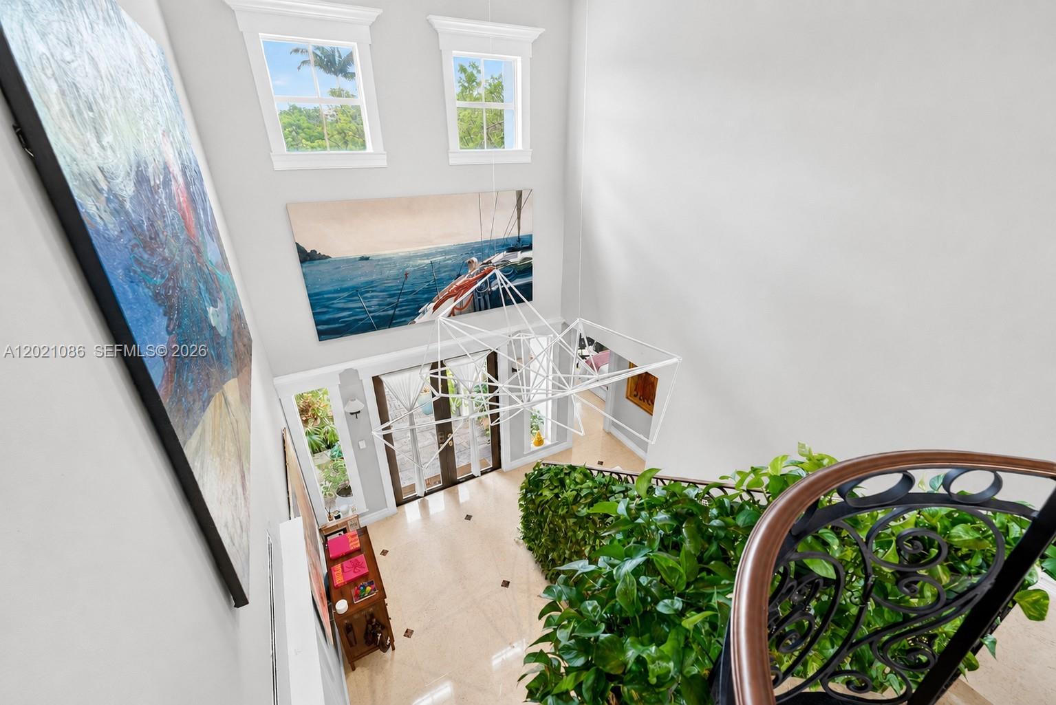 A high-angle view shows a double-height foyer with a modern chandelier, artwork, and indoor plants — 442 Ridgewood Rd, Key Biscayne FL 33149, KEY BISCAYNE, FL