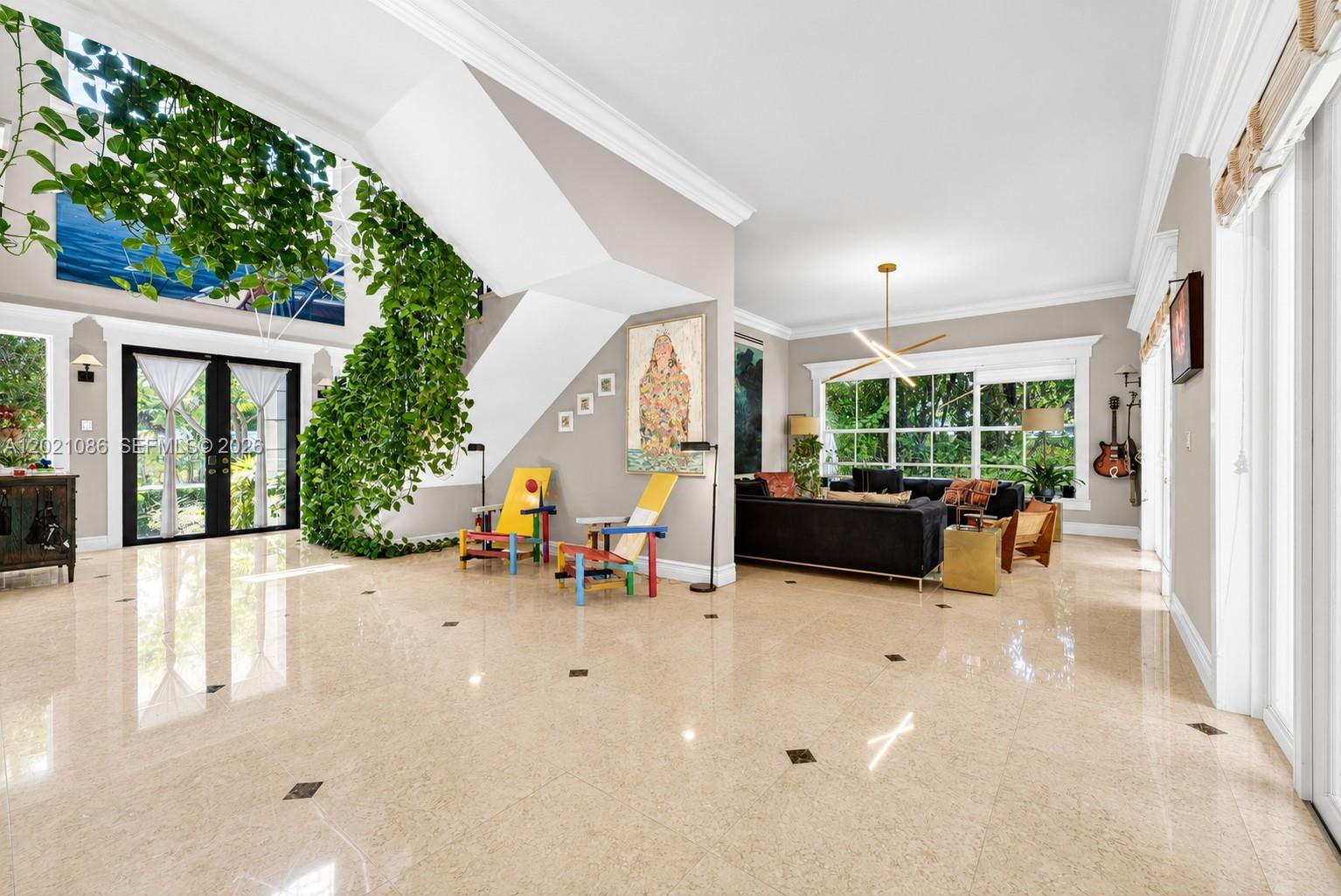A spacious living room features glossy tile floors, a grand staircase, and a large indoor plant — 442 Ridgewood Rd, Key Biscayne FL 33149, KEY BISCAYNE, FL