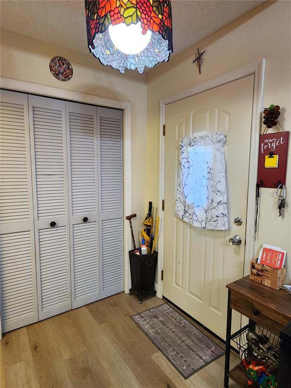 An entryway features light wood flooring, a louvered closet, a front door, and stained-glass lighting — 1701 SE 24TH ROAD UNIT 1601, OCALA, FL