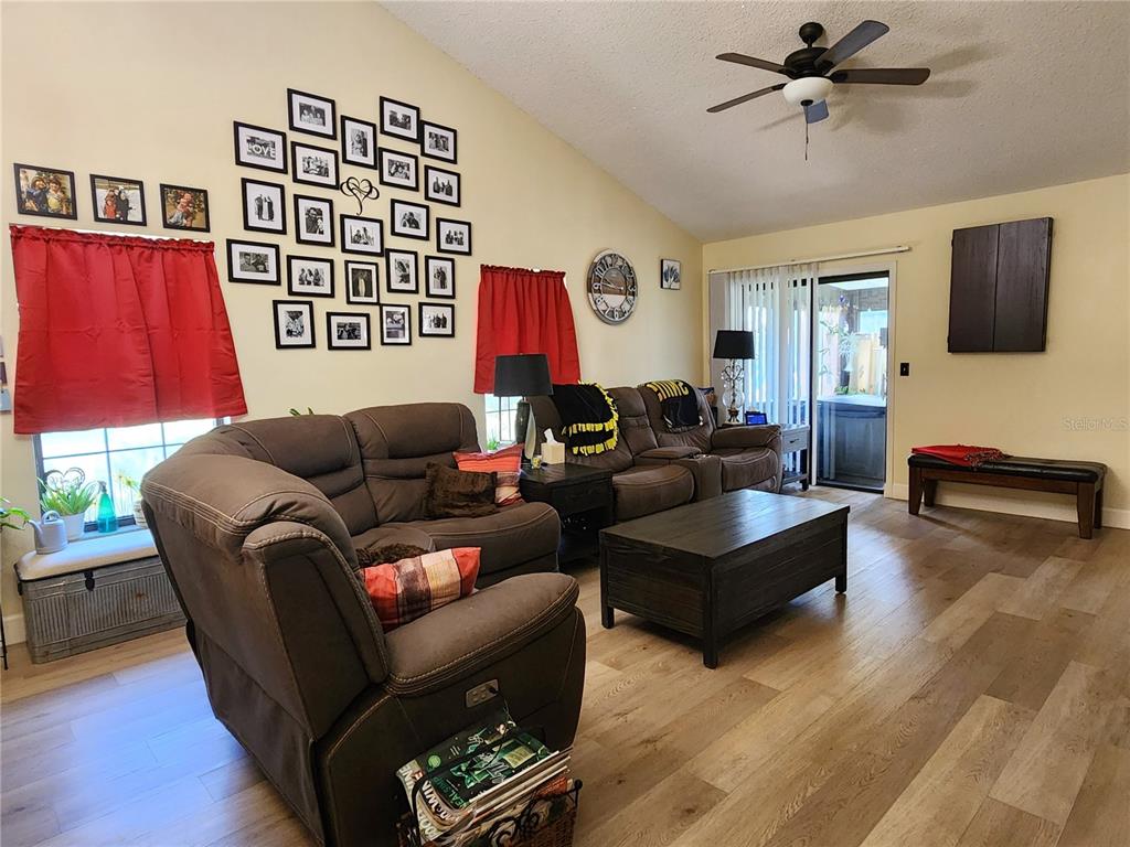 A living room features brown leather furniture, a gallery wall, and wood-look flooring — 1701 SE 24TH ROAD UNIT 1601, OCALA, FL