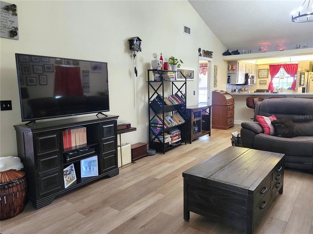 A living room features a television on a dark wood console, shelving, and wood flooring — 1701 SE 24TH ROAD UNIT 1601, OCALA, FL