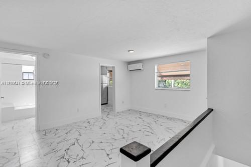 An interior room features white walls, marble-patterned tile flooring, and a wall-mounted air conditioning unit — 54 NW 62nd St # 4, Miami FL 33150, MIAMI, FL