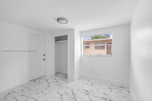 A bedroom with white walls, white marble-patterned tile flooring, a closet, and a window — 54 NW 62nd St # 4, Miami FL 33150, MIAMI, FL